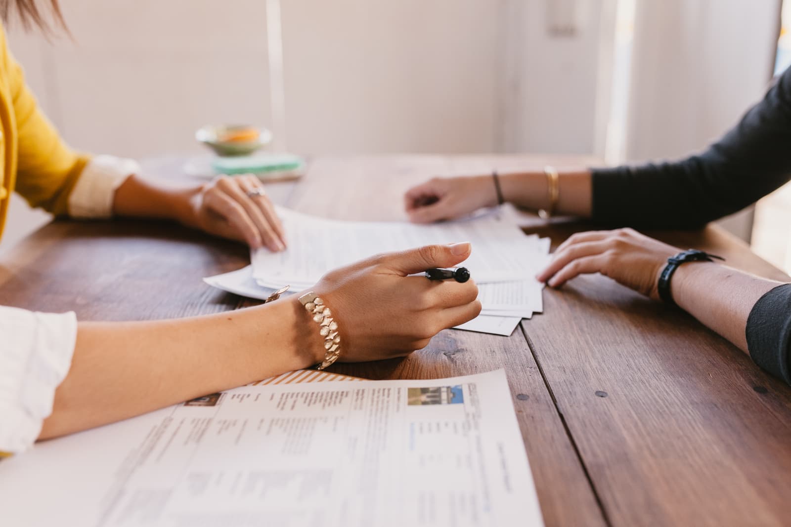 Two people reviewing documents across a timber table